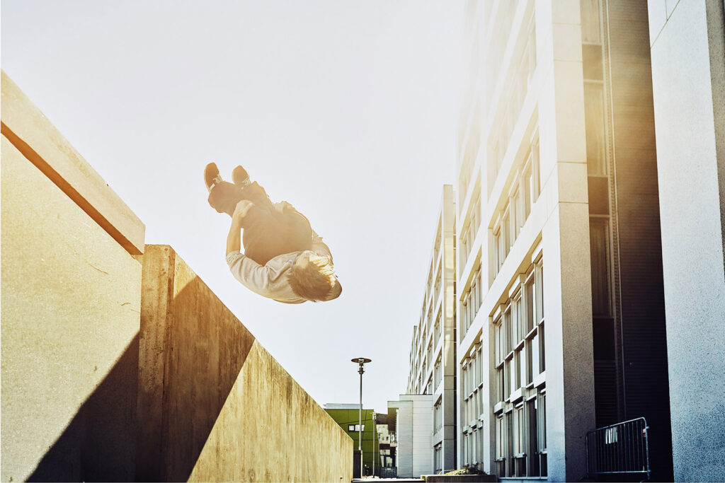 Streetrunner beim spektakulären Rückwärtssalto zwischen Betonmauern – urbane Actionfotografie aus einer modernen Werbekampagne von Atelier Schulte.