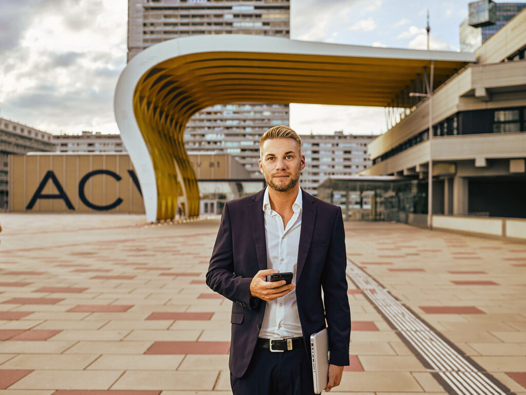 Professioneller Businessauftritt im Freien – Mann arbeitet am Laptop vor moderner Architektur in Wien, fotografiert von Atelier Schulte.
