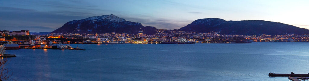 Sonnenaufgang über Bergen mit Blick auf die erleuchtete Küstenstadt und umliegende Berge – professionelle Landschafts- und Stadtfotografie von Atelier Schulte