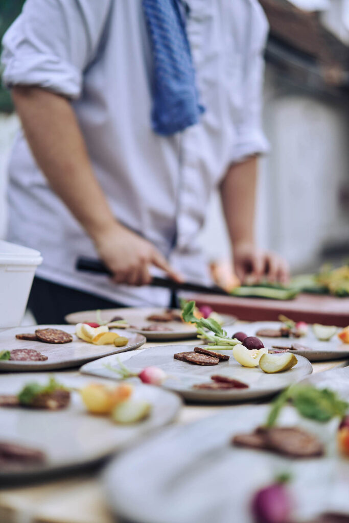 Reportagefotografie von Atelier Schulte – Koch bei der Vorbereitung regionaler Speisen bei ‚Essen vor Ort‘ am Wagram in Niederösterreich. Kulinarische Atmosphäre und Handwerk.