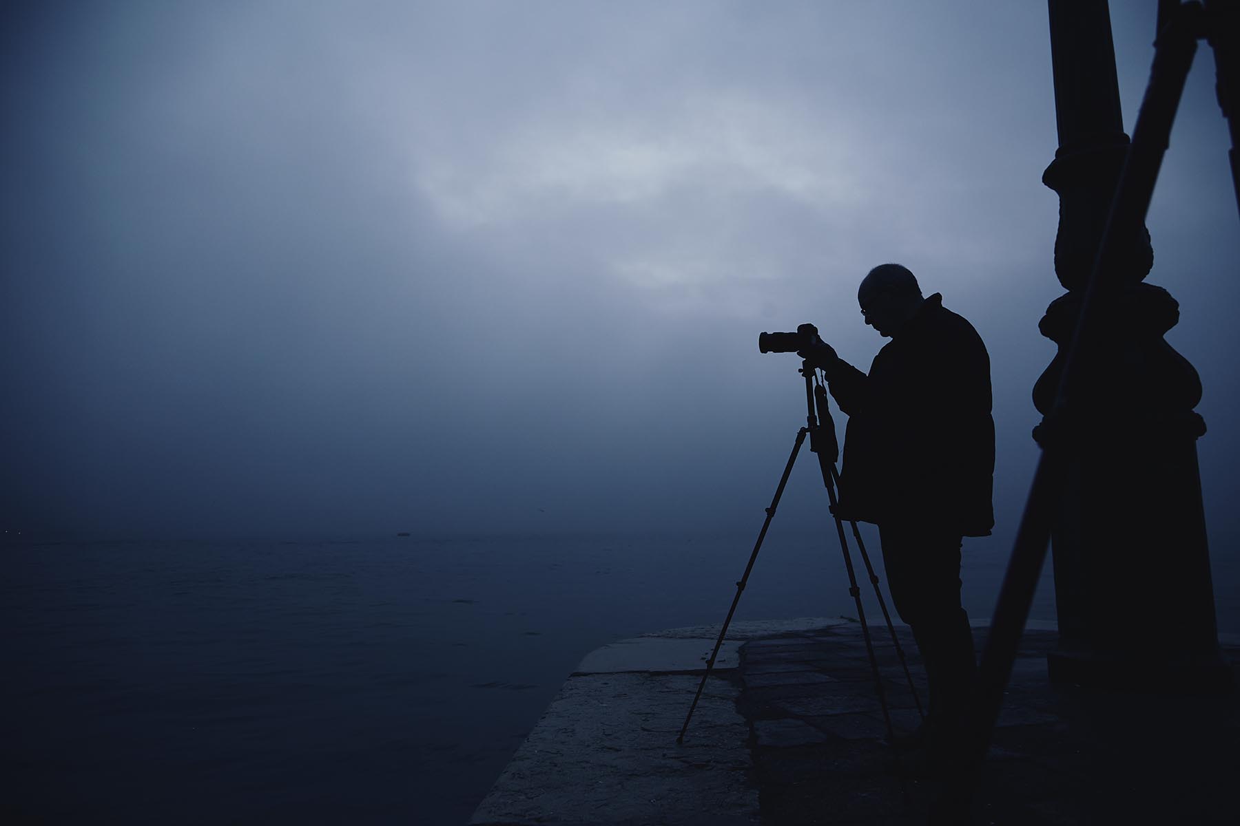 Fotograf mit Stativ im Nebel am Wasser, ruhige Morgenstimmung, Landschaftsfotografie Workshop Atelier Schulte