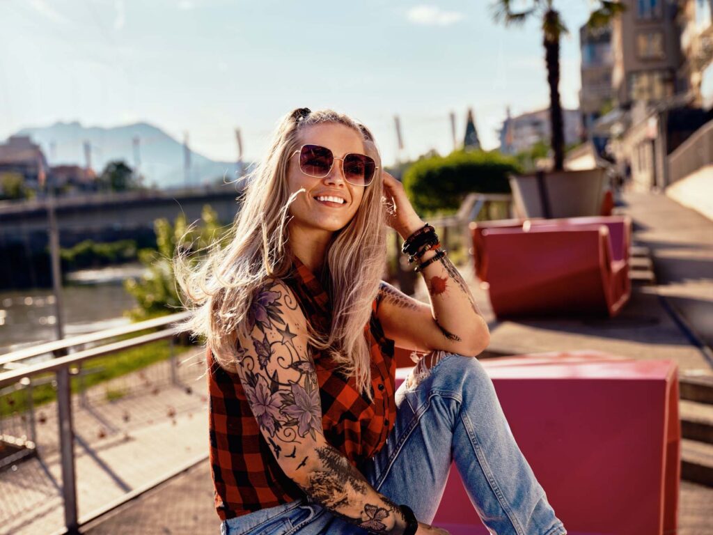 Lifestyle-Outdoor-Portrait einer Frau im urbanen Raum von Villach – entspanntes Sommermotiv mit Sonnenlicht, Skateboard und moderner Stadtkulisse in Kärnten