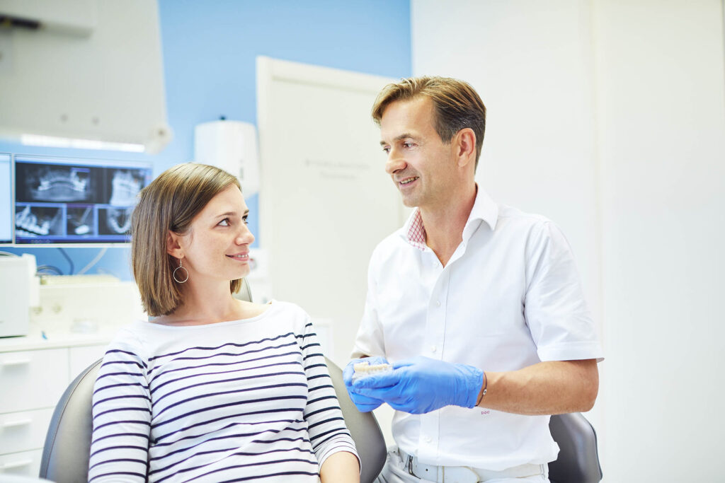 Zahnarzt im Beratungsgespräch mit Patientin – authentische Praxisfotografie für Vertrauen im Gesundheitswesen