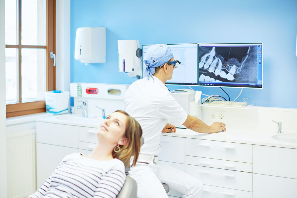 Zahnarzt analysiert Röntgenbild am Monitor – professionelle Praxisfotografie für Transparenz und Vertrauen im Gesundheitswesen