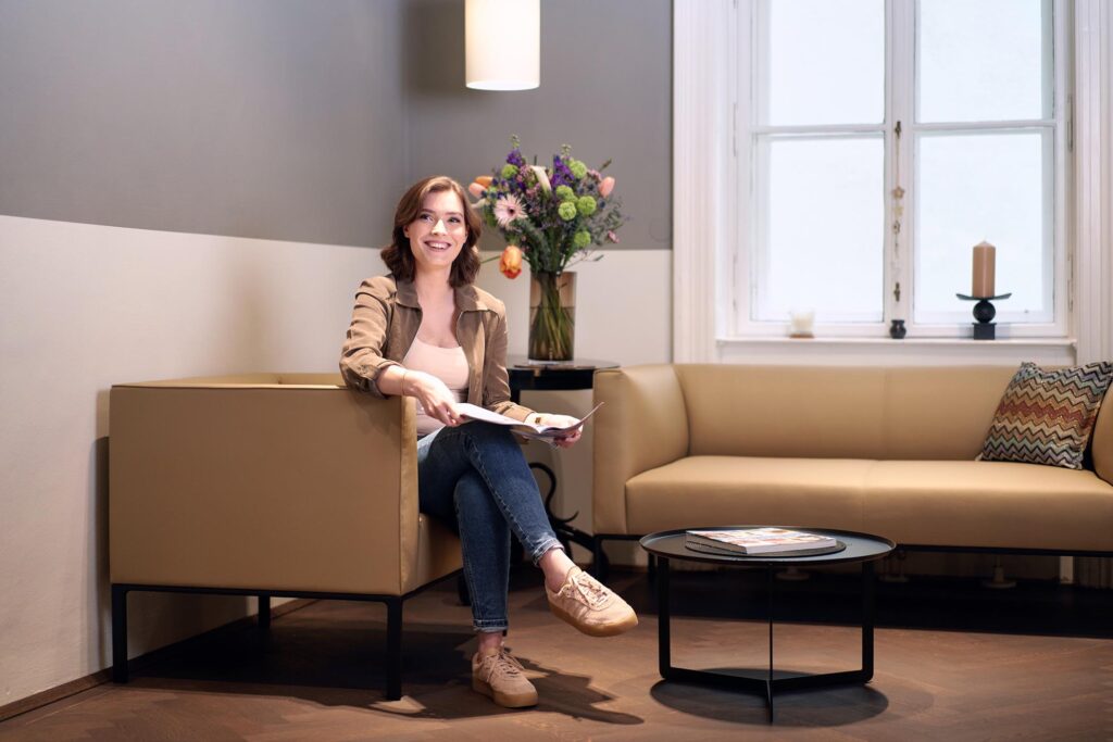 Patientin im Wartebereich einer modernen Zahnarztpraxis in Wien – ruhige, vertrauensvolle Atmosphäre.