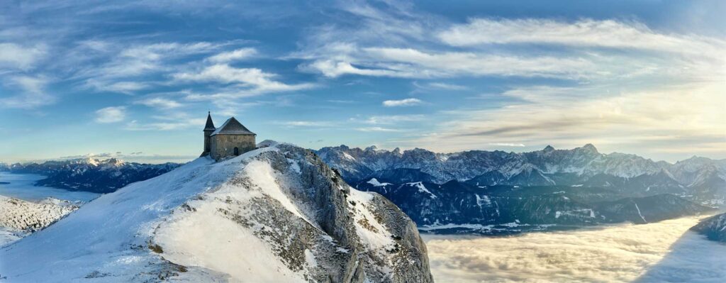 Winterliche Aufnahme der Gipfelkirche am Dobratsch mit Schnee, klarer Atmosphäre und weitem Blick über die Alpenlandschaft – fotografiert von Atelier Schulte.