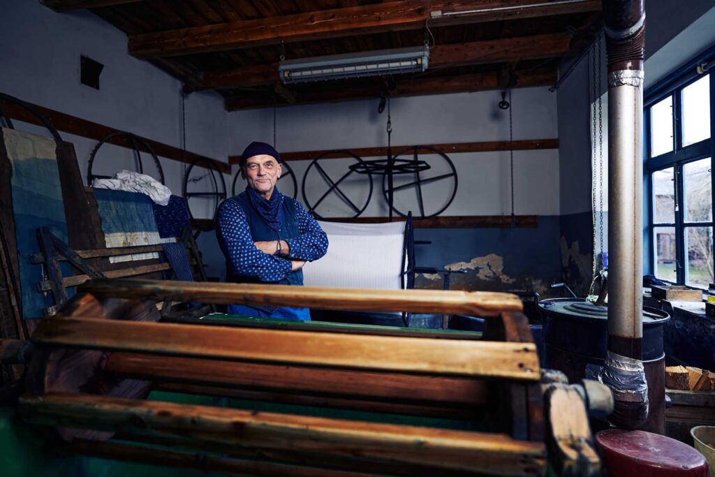 Authentisches Portrait eines Blaumachers in seiner Indigo-Blaudruckwerkstatt – Reportagefotografie aus dem Burgenland und traditionelles Handwerk in Österreich.