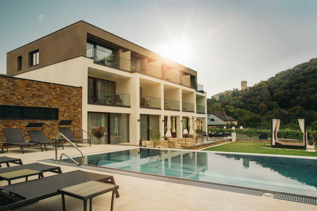 Hotelarchitektur in der Wachau mit Poolterrasse und klarer Fassadengliederung, eingebettet in die Landschaft. Architekturfotografie von Florian Schulte.