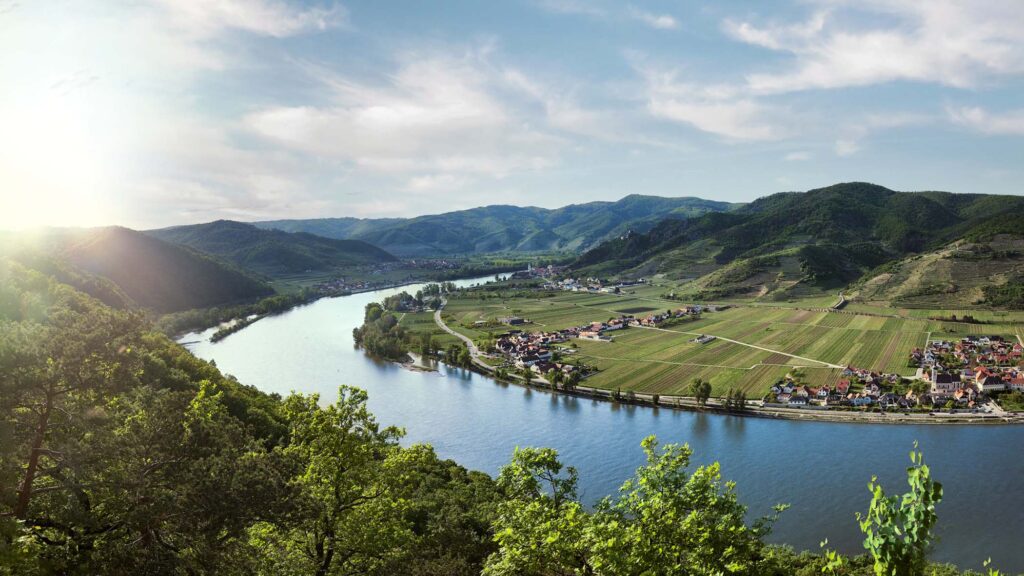 Weite Flusslandschaft in der Wachau mit Weinbergen und Ort im Morgenlicht, klar komponiert und bewusst reduziert – Landschaftsfotografie von Atelier Schulte