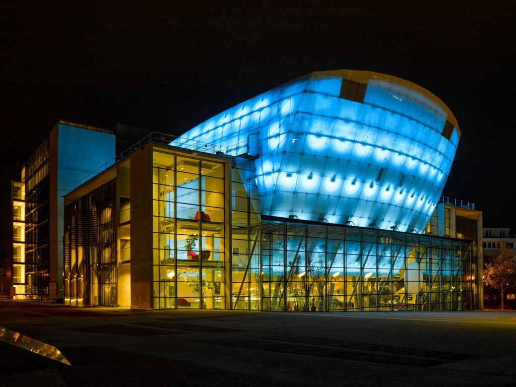 Nachtaufnahme des Museum Niederösterreich mit blau beleuchtetem Glasbau und klaren Linien. Architekturfotografie von Florian Schulte.