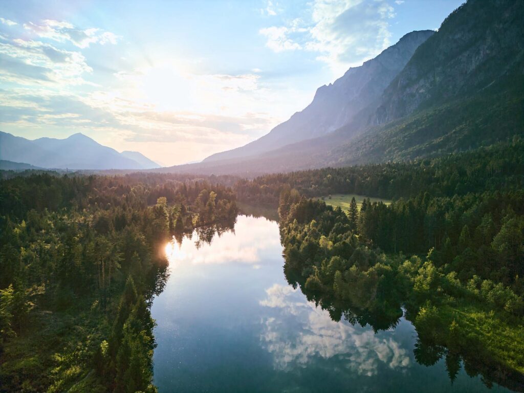 Alpine Flusslandschaft im Abendlicht mit Wald und Bergen, ruhige Landschaftsfotografie mit ausgewogener Bildbearbeitung