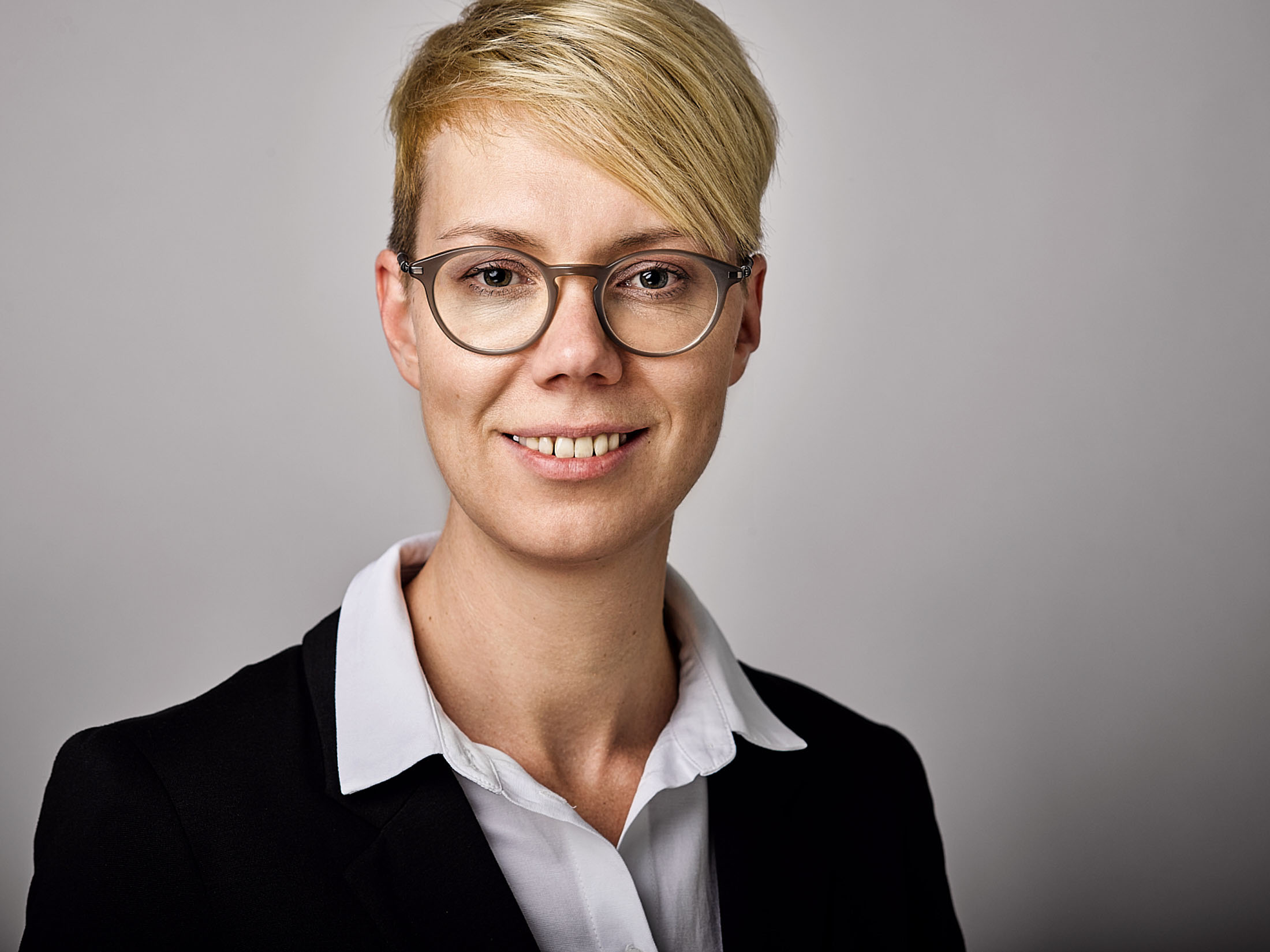 Businessportrait einer Mitarbeiterin vor neutralem Hintergrund – professionelle Businessfotografie in Österreich, Atelier Schulte.