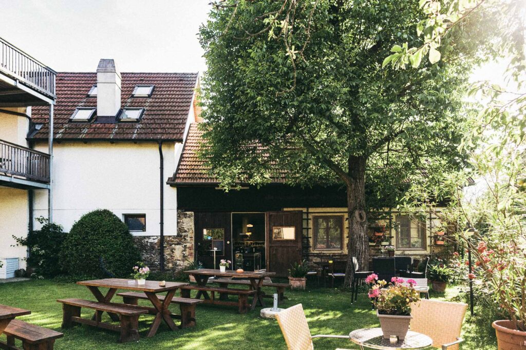 Holzverkleideter Balkon eines Gästehauses in der Wachau im warmen Sommerlicht – architektonische Außenansicht, dokumentiert in einer analogen Architekturreportage von Atelier Schulte.