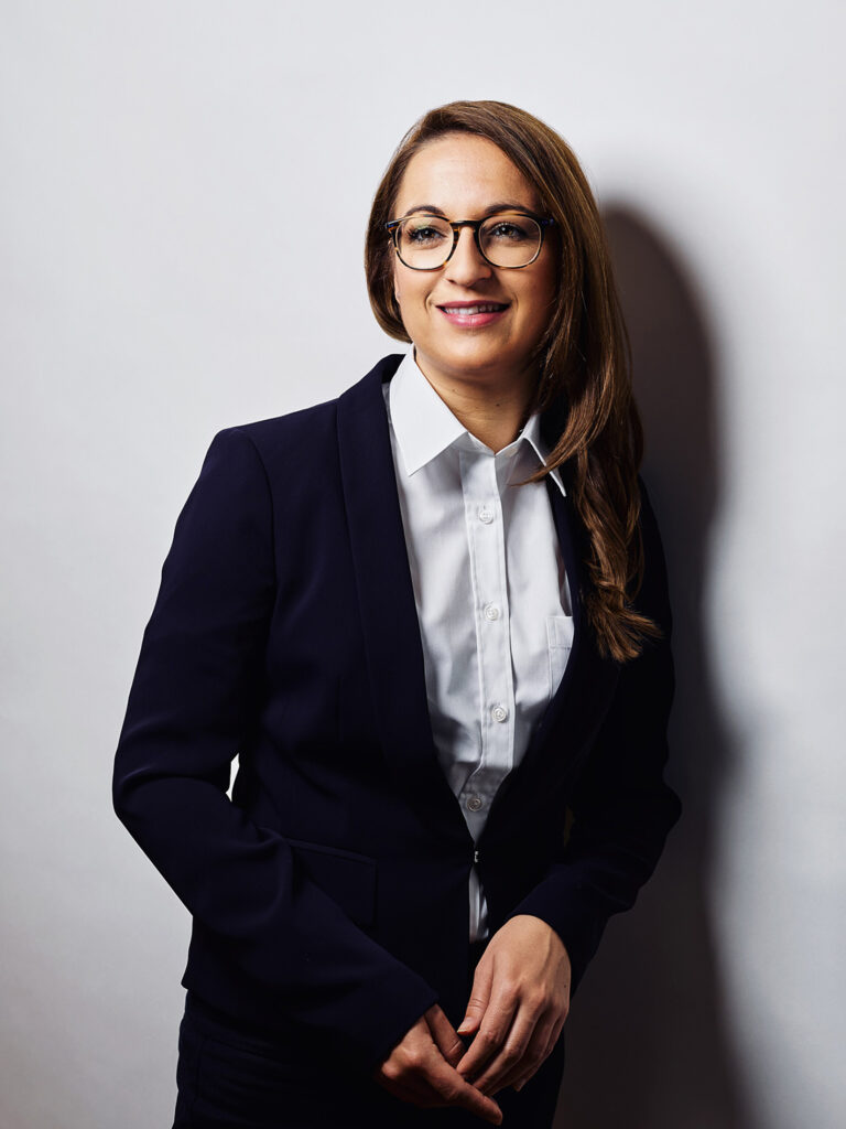 Businessportrait einer Frau vor hellem Hintergrund, aufgenommen in klassischem Portraitlicht.