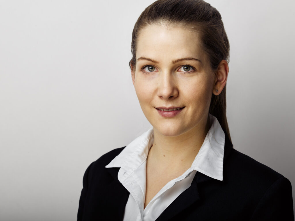 Businessportrait einer Mitarbeiterin vor neutralem Hintergrund mit klarer, professioneller Lichtführung.
