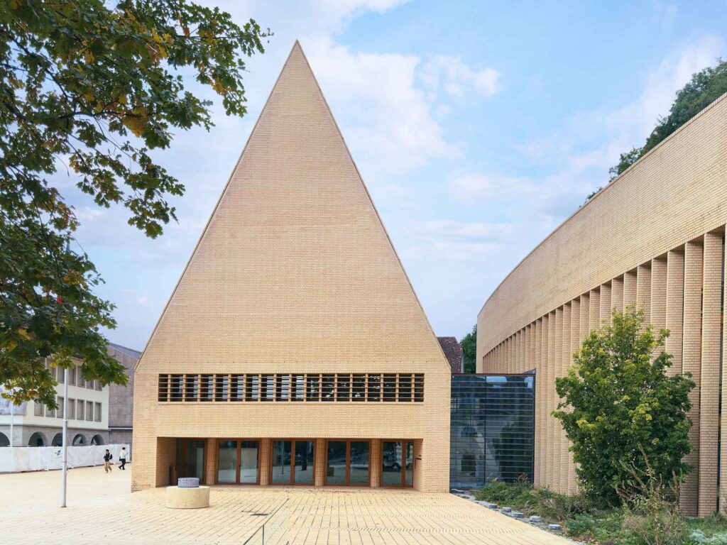 Moderne Architekturfotografie eines Gebäudes mit markanter dreieckiger Form und Ziegelfassade – fotografiert von Florian Schulte, Architekturfotograf in Österreich