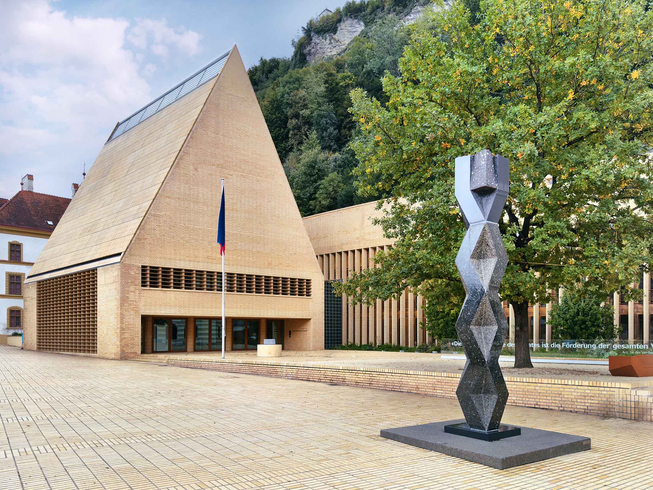 Architekturfotografie eines modernen Gebäudes mit Ziegelfassade und Skulptur im öffentlichen Raum – fotografiert von Florian Schulte, Architekturfotograf in Österreich