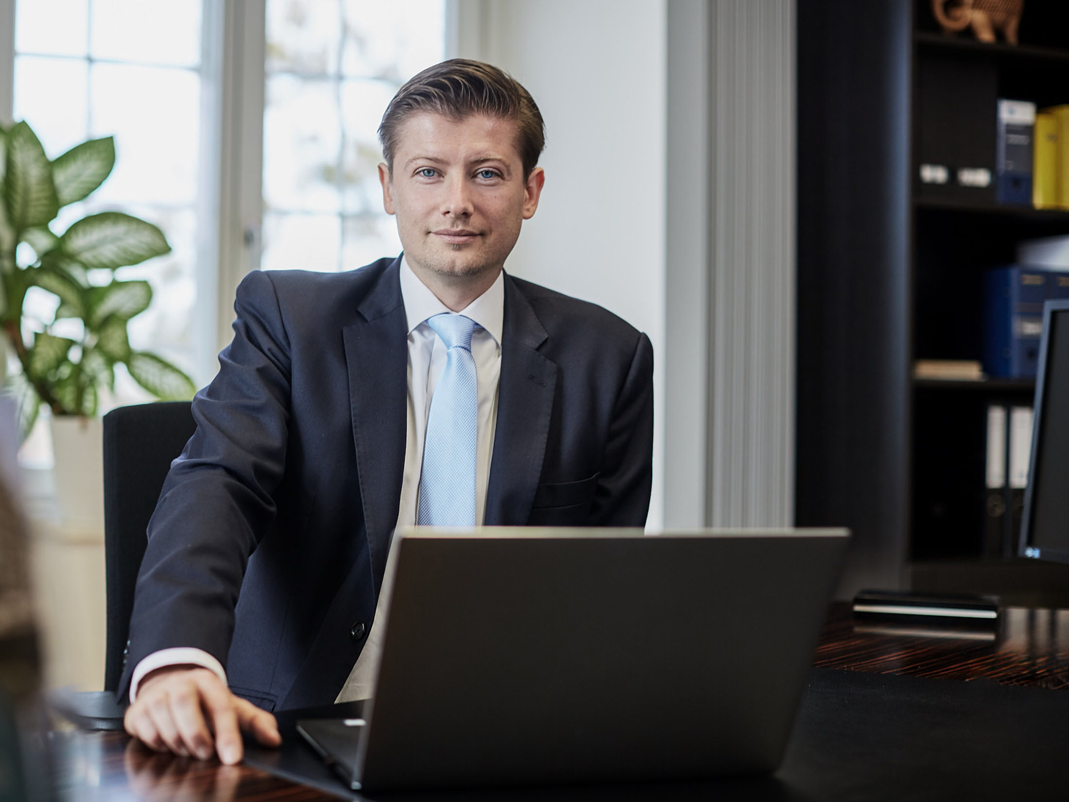 Geschäftsführer sitzt im Büro am Schreibtisch vor einem Laptop, aufgenommen in professioneller Business-Umgebung.