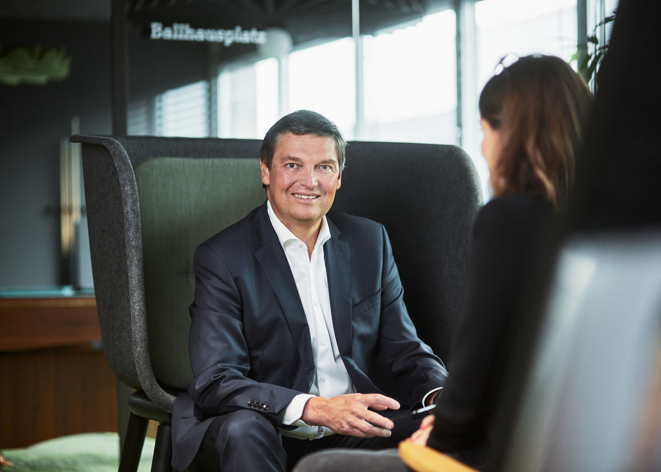 Businessportrait eines Mitarbeiters in einer modernen Gesprächssituation; gezeigt wird ein professionelles Setting zur Illustration von Aufwand, Planung und Kostenfaktoren bei Mitarbeiterfotos in Unternehmen.