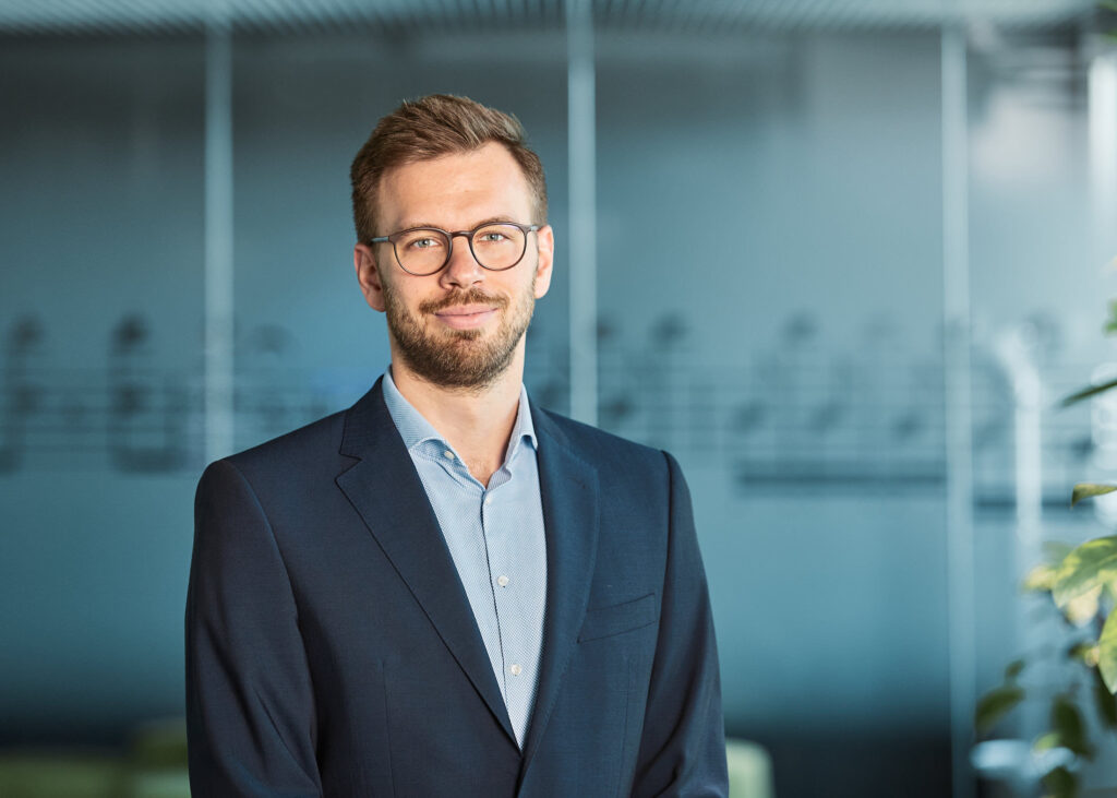 Professionelles Businessportrait eines Mitarbeiters im modernen Unternehmensumfeld; Beispiel für authentische Mitarbeiterfotos, die Wirkung, Wiedererkennungswert und Kostenfaktoren bei Businessportraits zeigen.