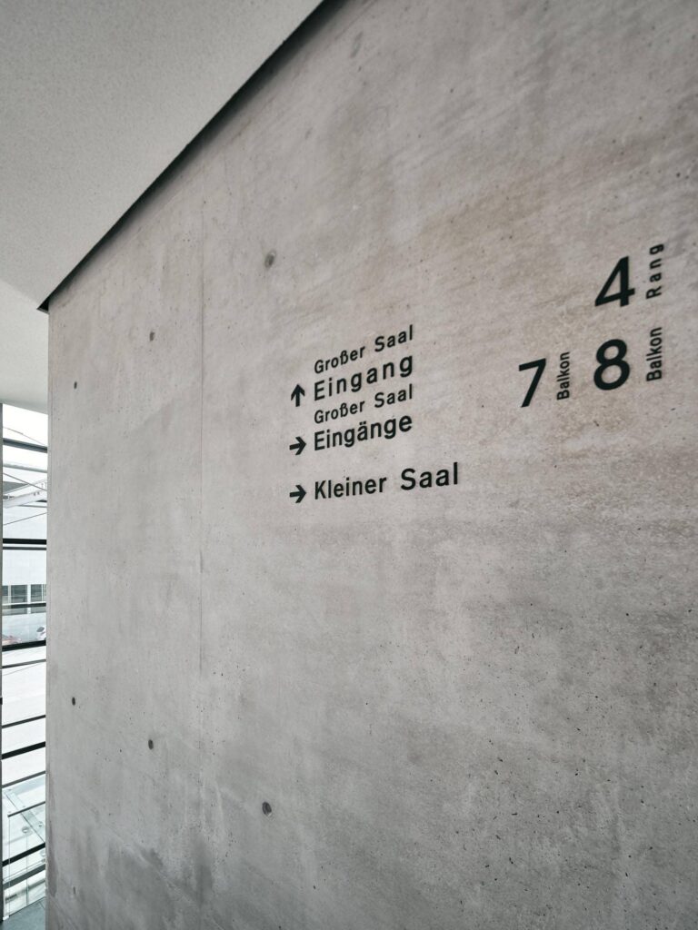 Detailaufnahme des Leitsystems im Festspielhaus St. Pölten mit Betonwand und klarer Typografie – Architekturfotografie von Florian Schulte, Atelier Schulte, Spezialist für Architekturfotografie in Österreich
