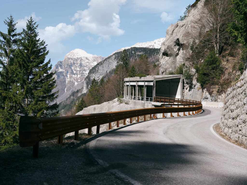 Straße als Linie entlang einer Felswand mit Schutzbauwerk in alpiner Berglandschaft