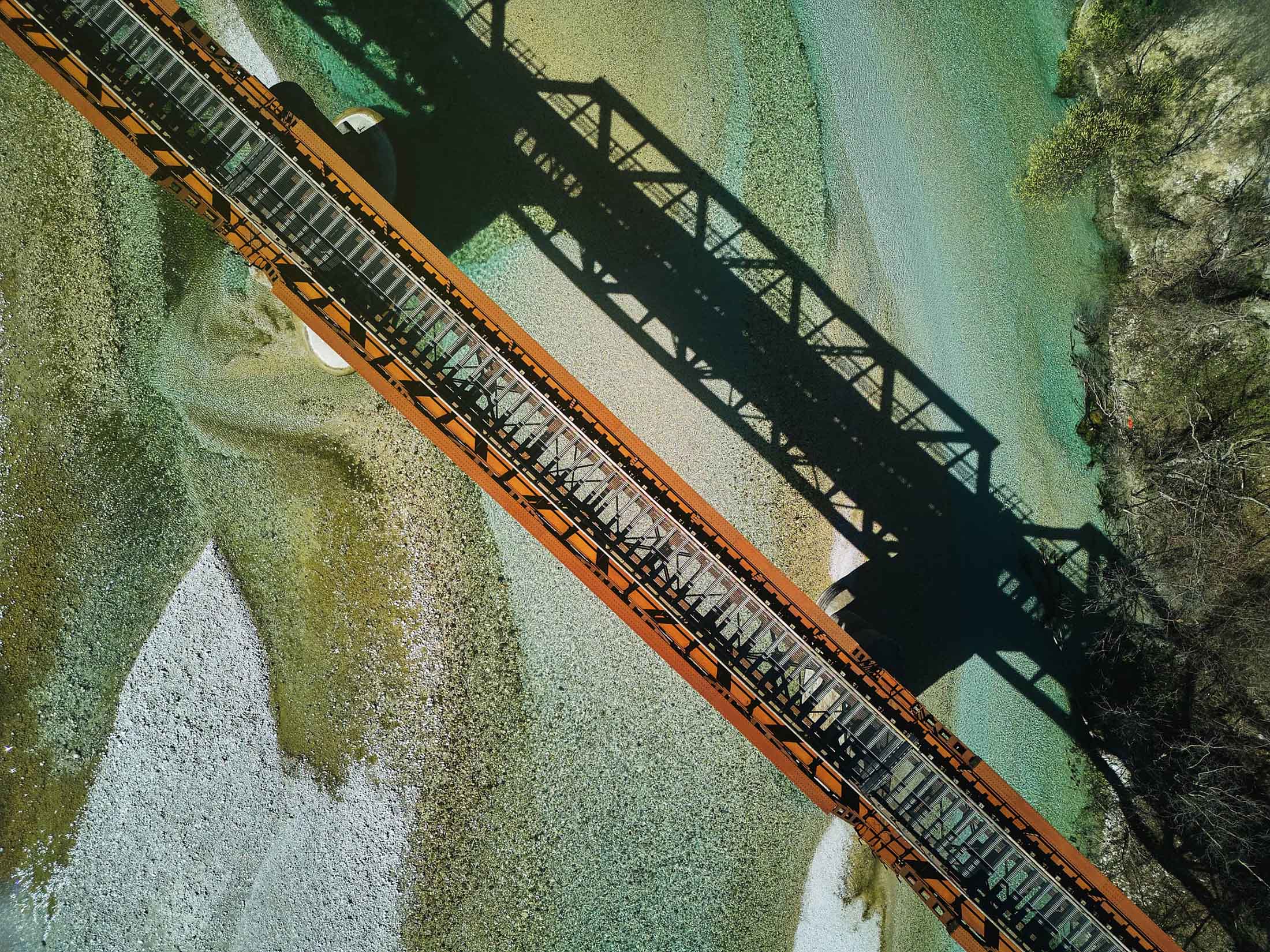Brücke als klare Linie über einem Fluss, sichtbar durch Schatten und Struktur aus der Vogelperspektive