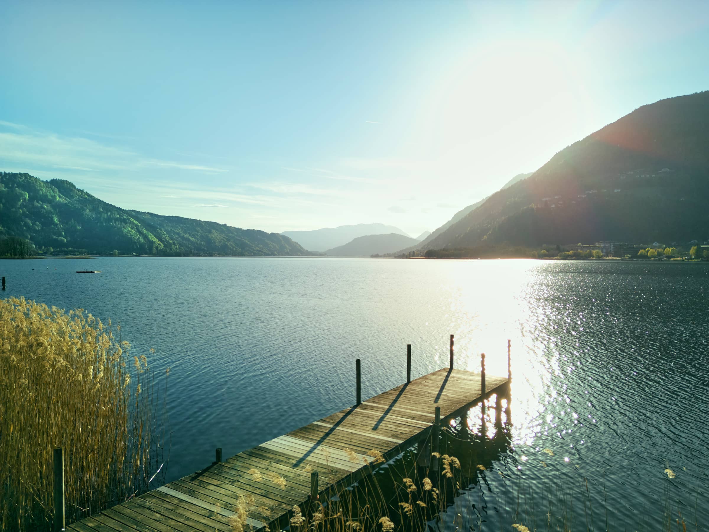 Steg am Ossiacher See in Kärnten – ruhige Landschaftsfotografie mit Wasser, Bergen und Lichtreflexion im Gegenlicht, aufgenommen von Fotograf Florian Schulte