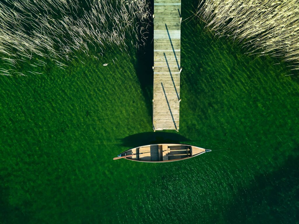 Drohnenaufnahme am Ossiacher See in Kärnten – Holzsteg und Boot im klaren Wasser, minimalistische Landschaftsfotografie von Fotograf Florian Schulte