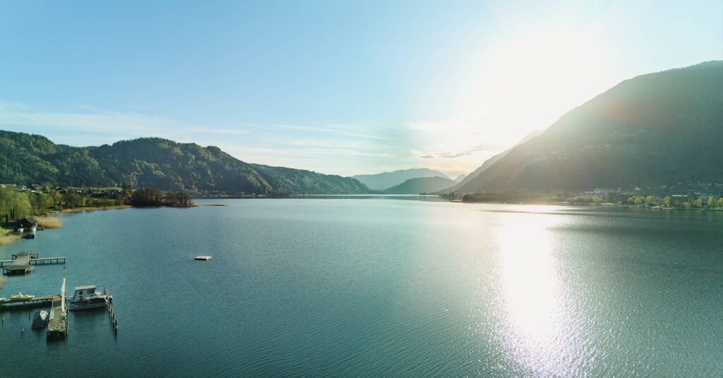 Ossiacher See in Kärnten bei tiefstehender Sonne – weite Alpenlandschaft mit Spiegelungen im Wasser, fotografiert von Fotograf Florian Schulte