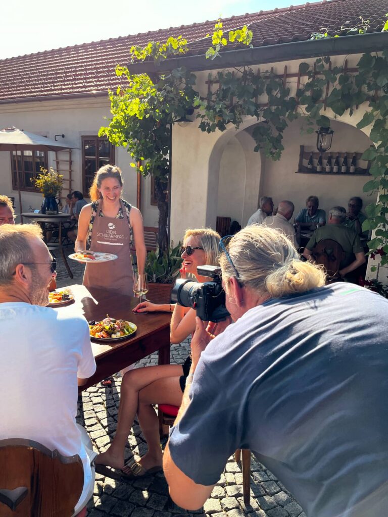 Businessfotograf bei einem Outdoor-Shooting in einem Gastgarten – authentische Businessfotografie mit natürlicher Interaktion und realer Arbeitssituation in Österreich
