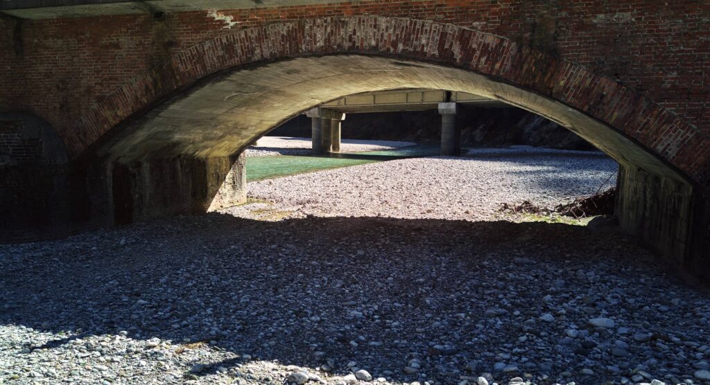 Raum unter einer Brücke sichtbar durch Licht und Schatten über einem Flussbett