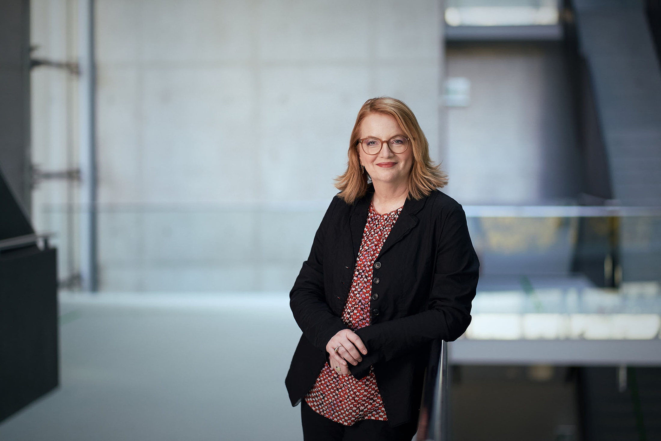 Businessportrait einer Mitarbeiterin in moderner Unternehmensarchitektur – professionelle Businessfotografie in Österreich, Atelier Schulte