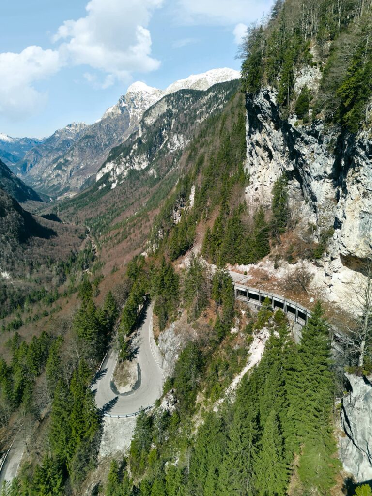 Luftaufnahme einer alpinen Serpentinenstraße zwischen Felsen und Wald im Alpen-Adria-Raum – ruhige Landschaftsfotografie und Aerials von Atelier Schulte mit natürlichem Licht und klarer Linienführung.
