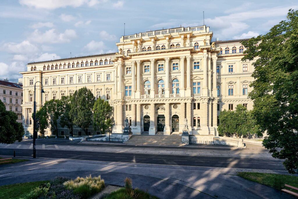 Historische Fassade eines Wiener Justizgebäudes im Abendlicht, klar und frontal fotografiert, eingebettet in den urbanen Stadtraum.