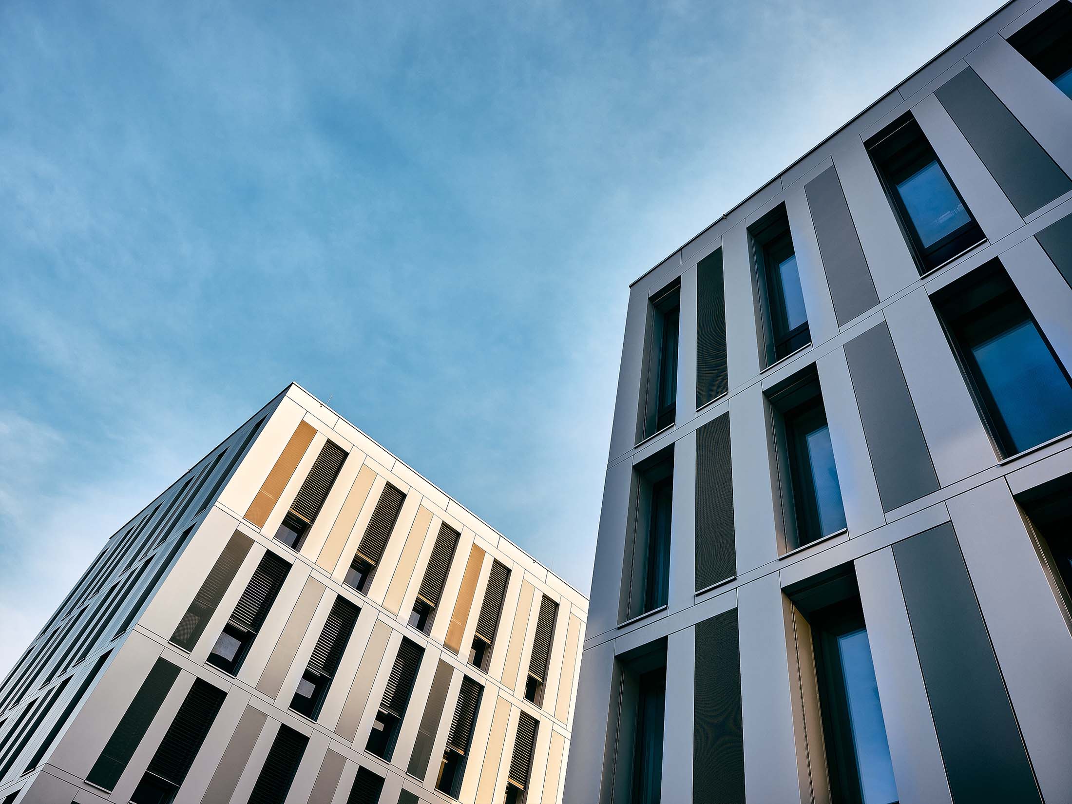 Moderne Fassaden mit klaren vertikalen Linien und ruhigem Abendlicht, fotografiert im urbanen Raum mit Fokus auf Geometrie und Materialität.