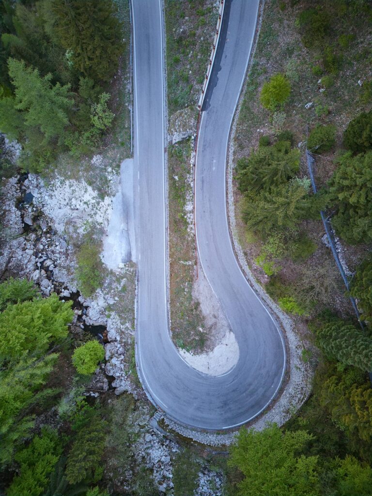 Aerials einer alpinen Serpentine zwischen Wald und Felsen im Alpen-Adria-Raum – moderne Drohnenfotografie und Landschaftsfotografie für Outdoor- und Tourismusprojekte.